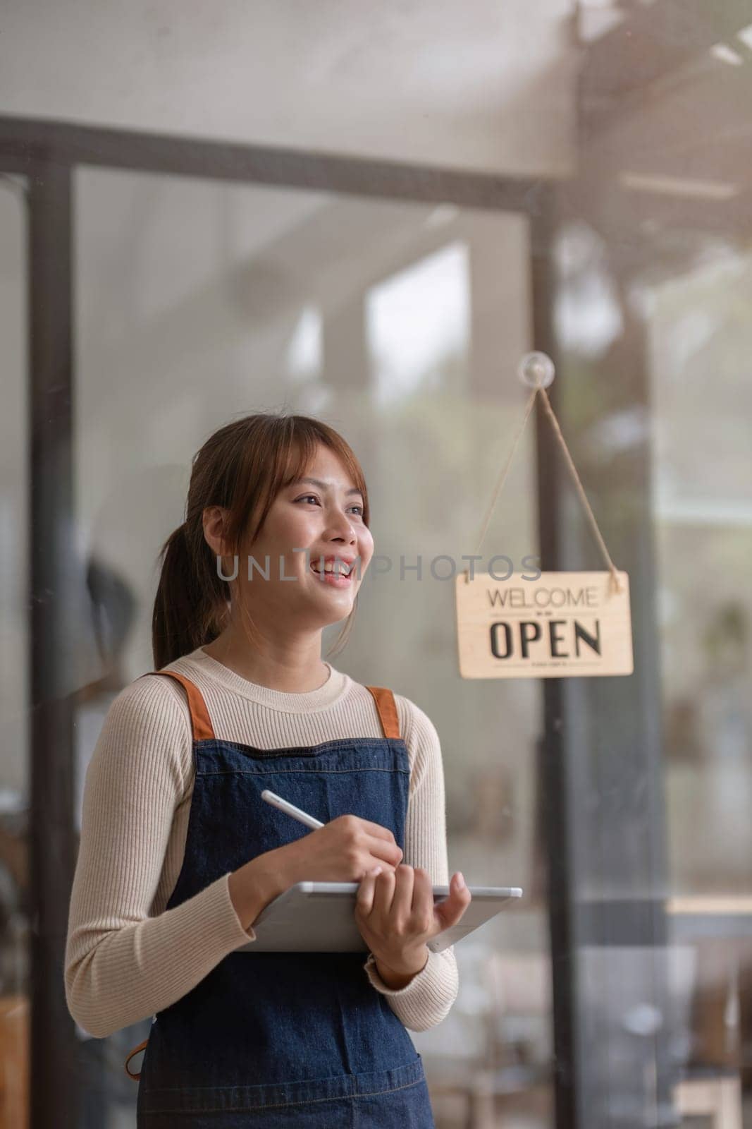 Successful small business owner. Beautiful girl with apron holding tablet standing in coffee shop restaurant. Portrait of asian woman barista cafe owner..