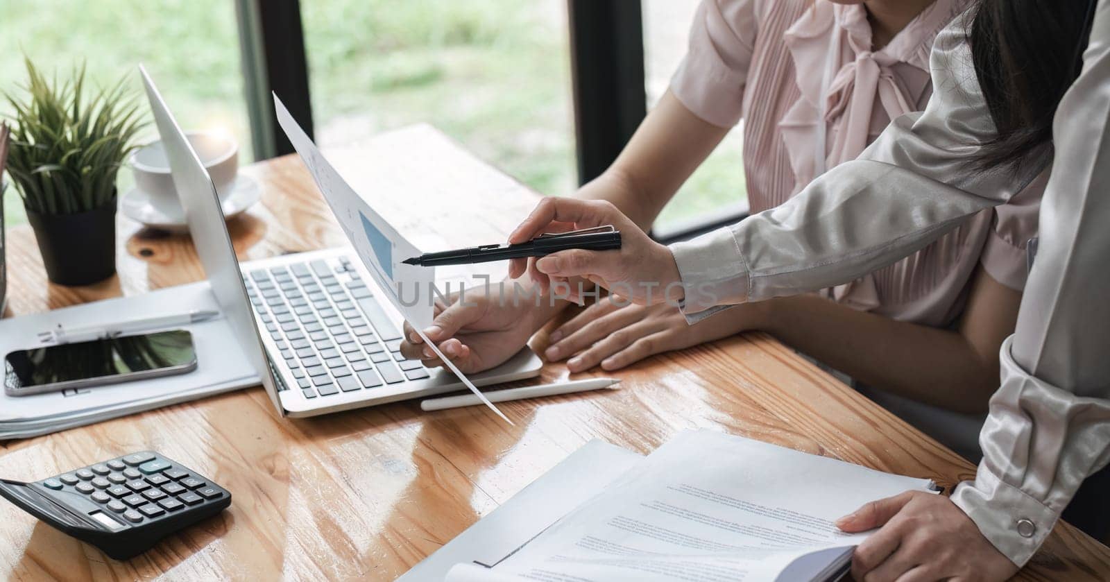 Business team together to make investment plan at the meeting. Close-up of business advisor pointing to graph and chart analyzing company financial report by wichayada