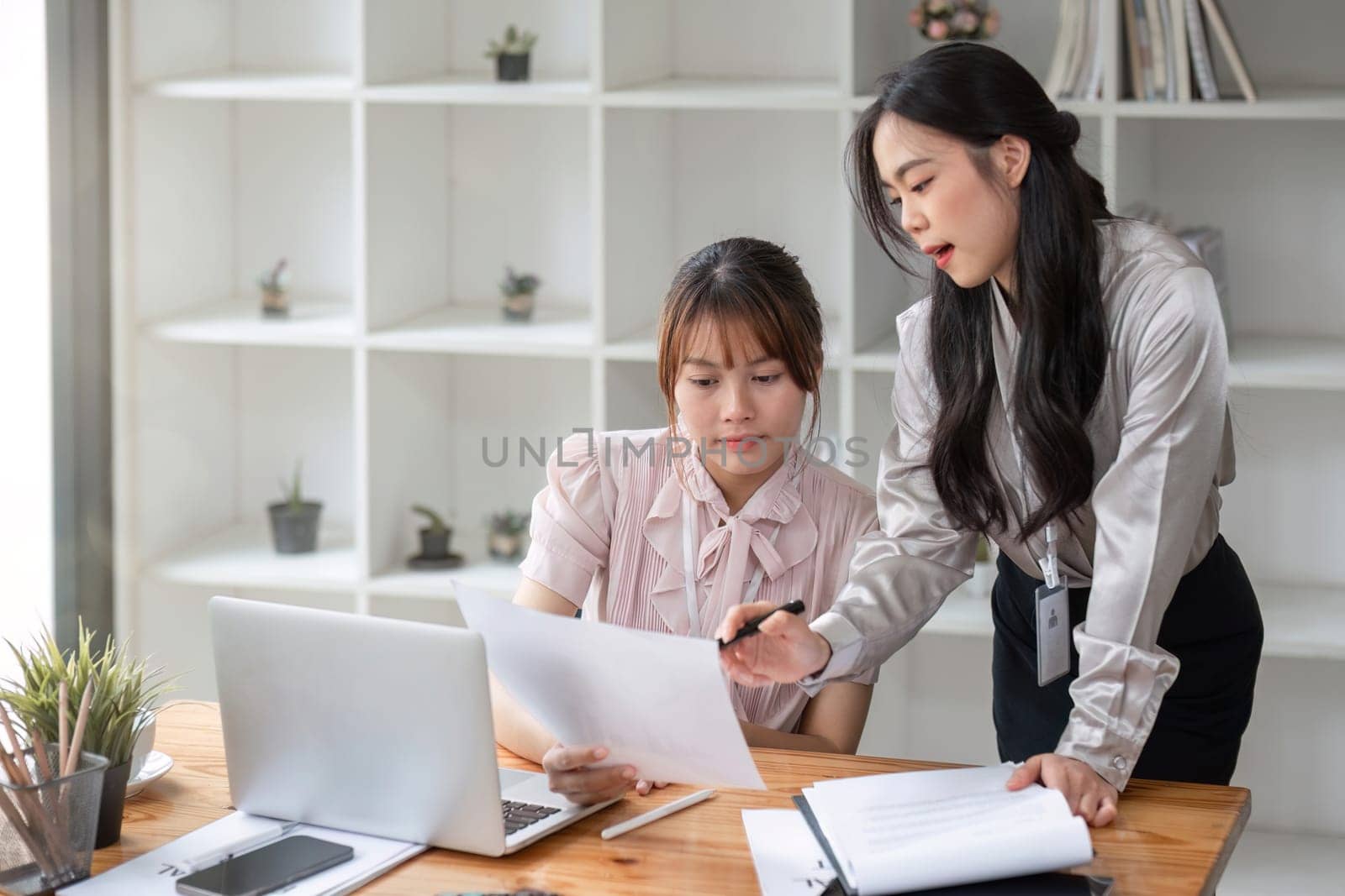 Two Young Asian businesswoman discuss with new startup project Idea presentation, analyze statistics and investment market at office by wichayada