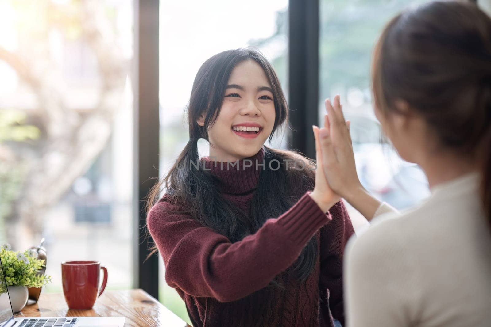Portrait of two best friends classmates giving high five success celebrate her best friend while doing homework.