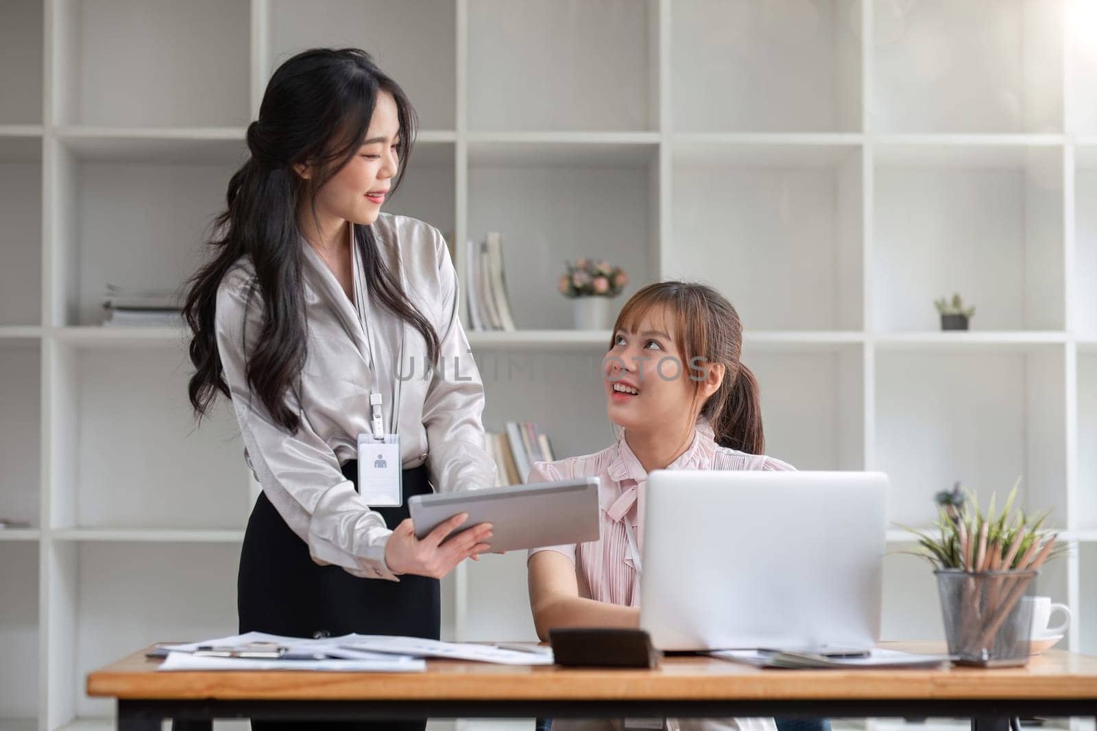 Two Young Asian businesswoman discuss with new startup project Idea presentation, analyze statistics and investment market at office.