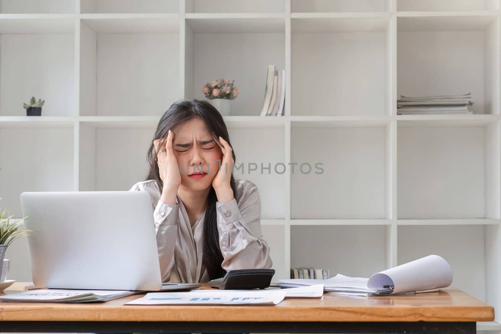 businesswoman looking stressed out while working in an office. Stressed business woman working from on laptop looking worried, tired and overwhelmed by wichayada