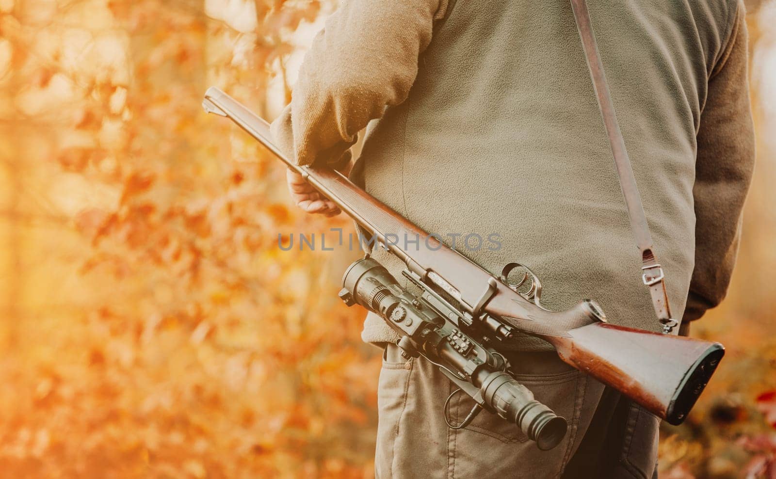 Hunter or ranger with gun or rifle in a forest hunting of some venison, hunting period, autumn season, hunting and people concept