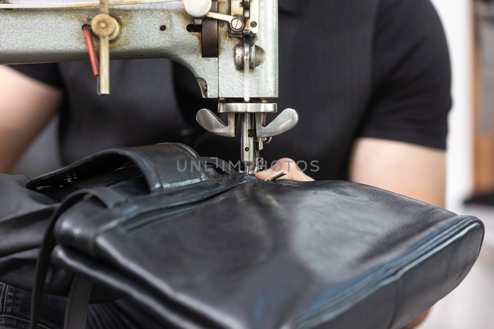 Black leather bag repair in a tailoring studio, leatherworking concept