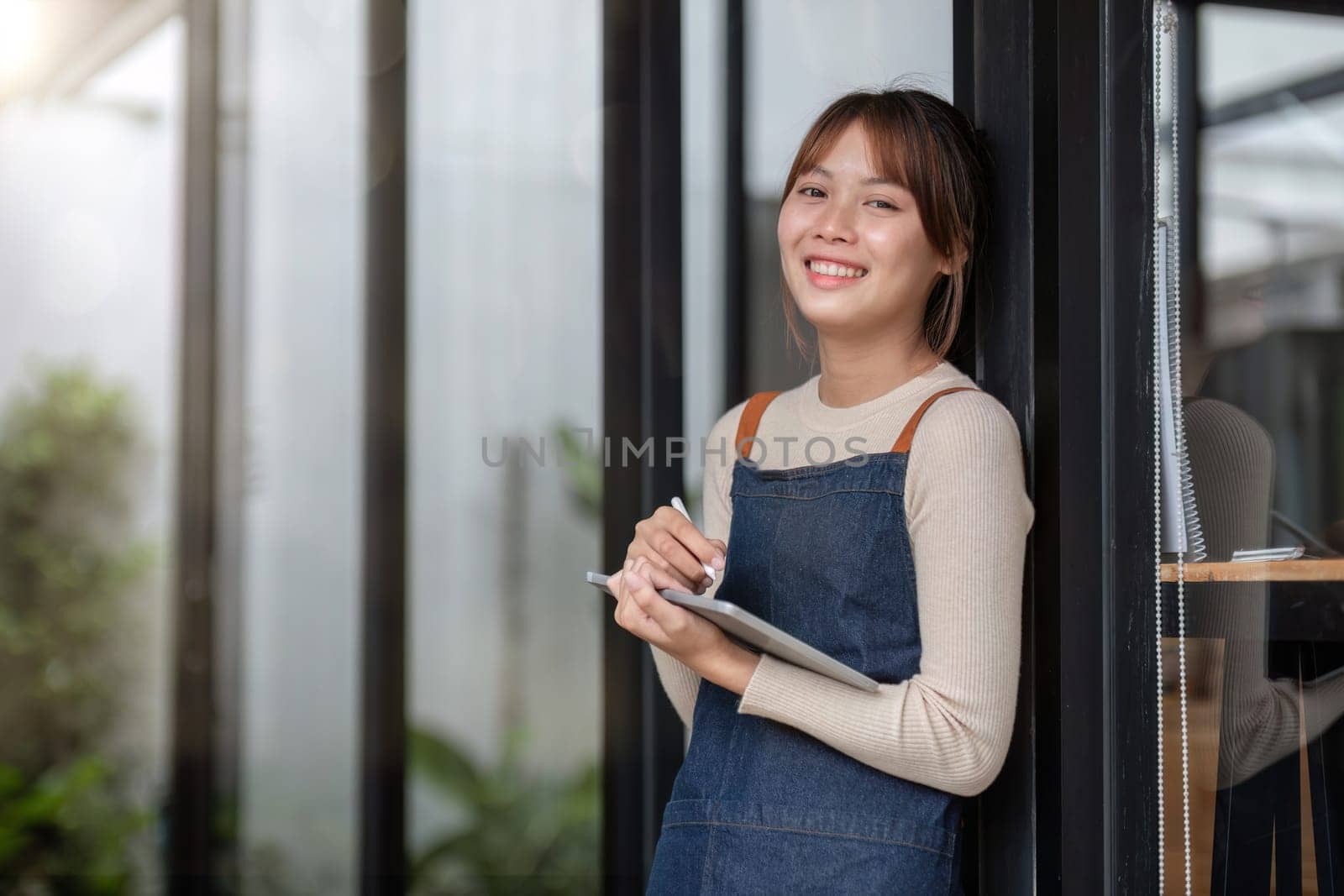 Asian coffee shop owner or barista smiling at coffee shop and holding tablet Female small business owner in food and beverage by wichayada