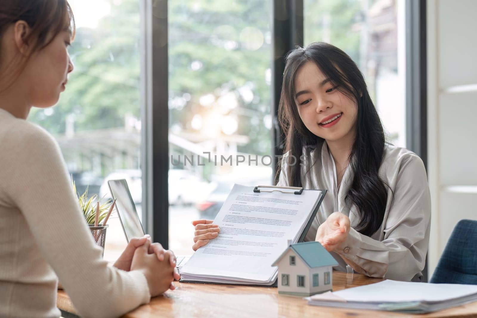 Real estate agent discuss about the terms of the home purchase agreement and asked the customer to sign the documents to make the contract legally, Home sales, lease, mortgage and home insurance. by wichayada