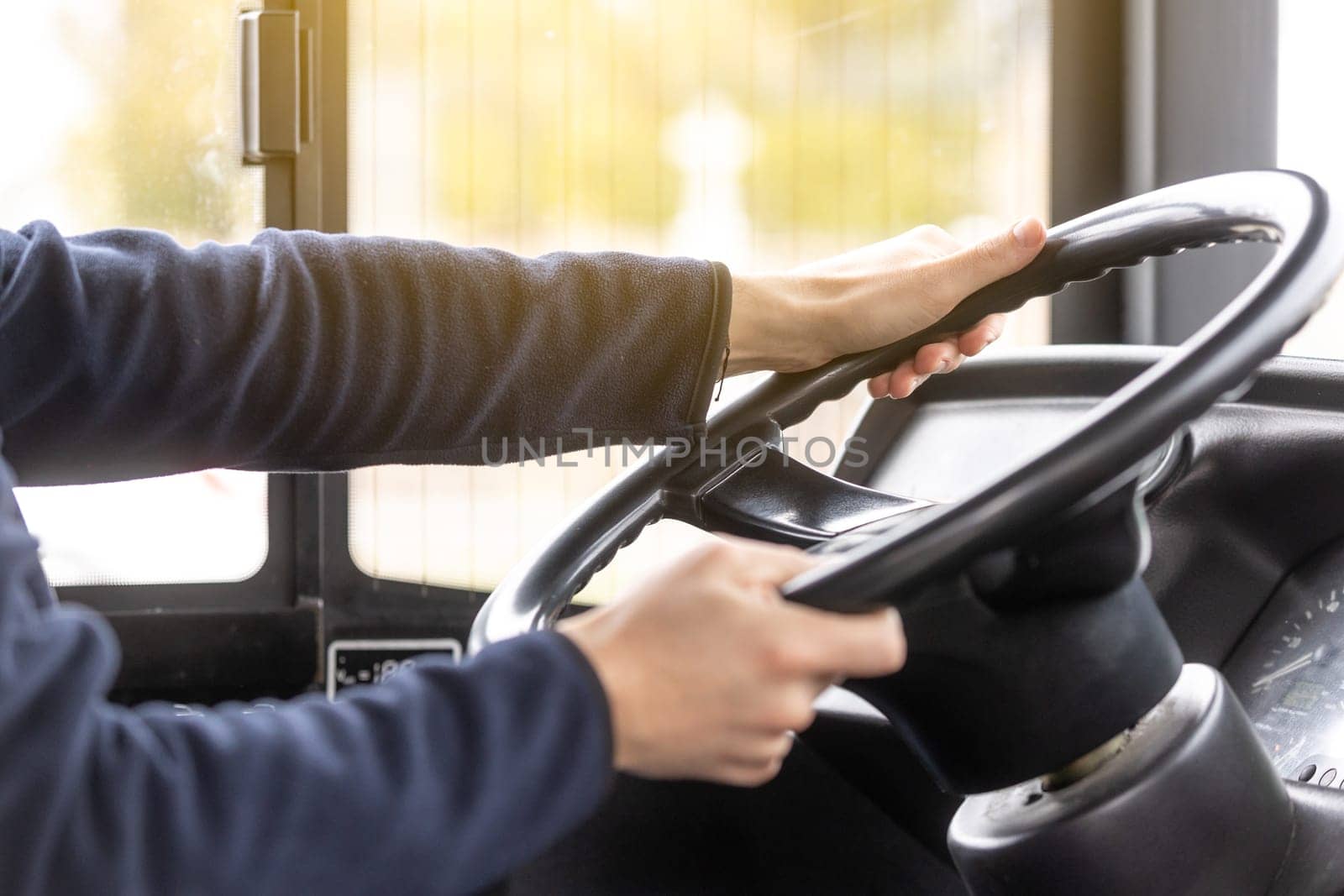 Close up of bus driver hands on the steering wheel during driving the bus, public transport concept by Kadula
