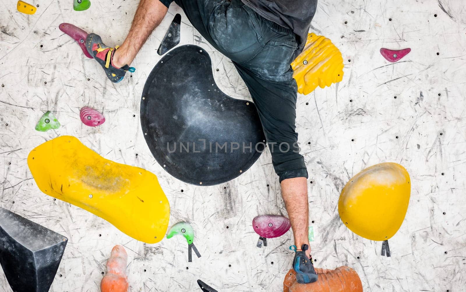 Young man climbing on the indoor climbing wall with a chalked hands