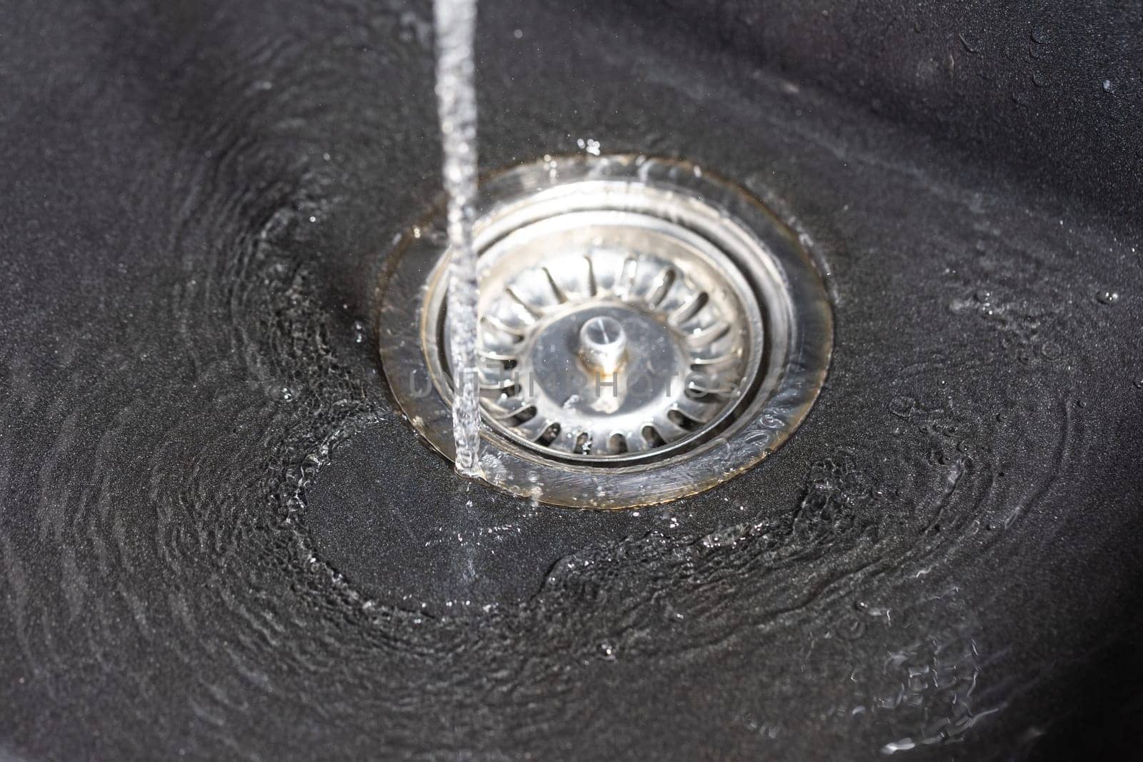 The water falling down from faucet to stainless sink and flow down to a water hole, drink concept