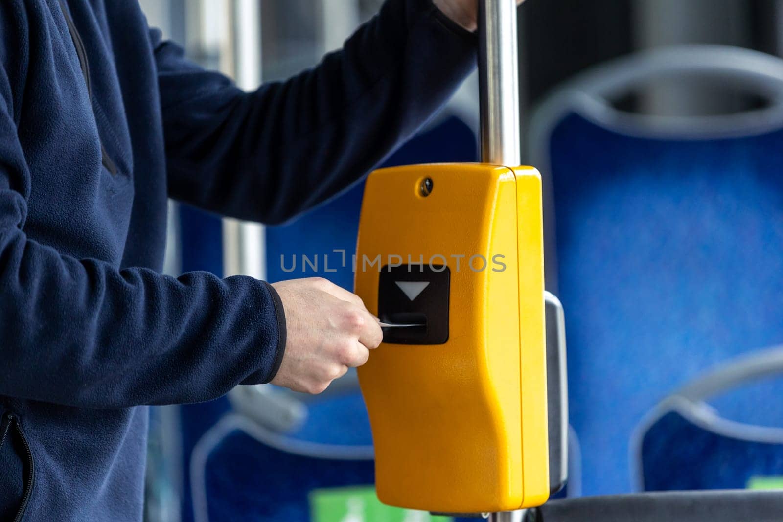 Young man hand inserts the bus ticket into a validator, validating and ticking