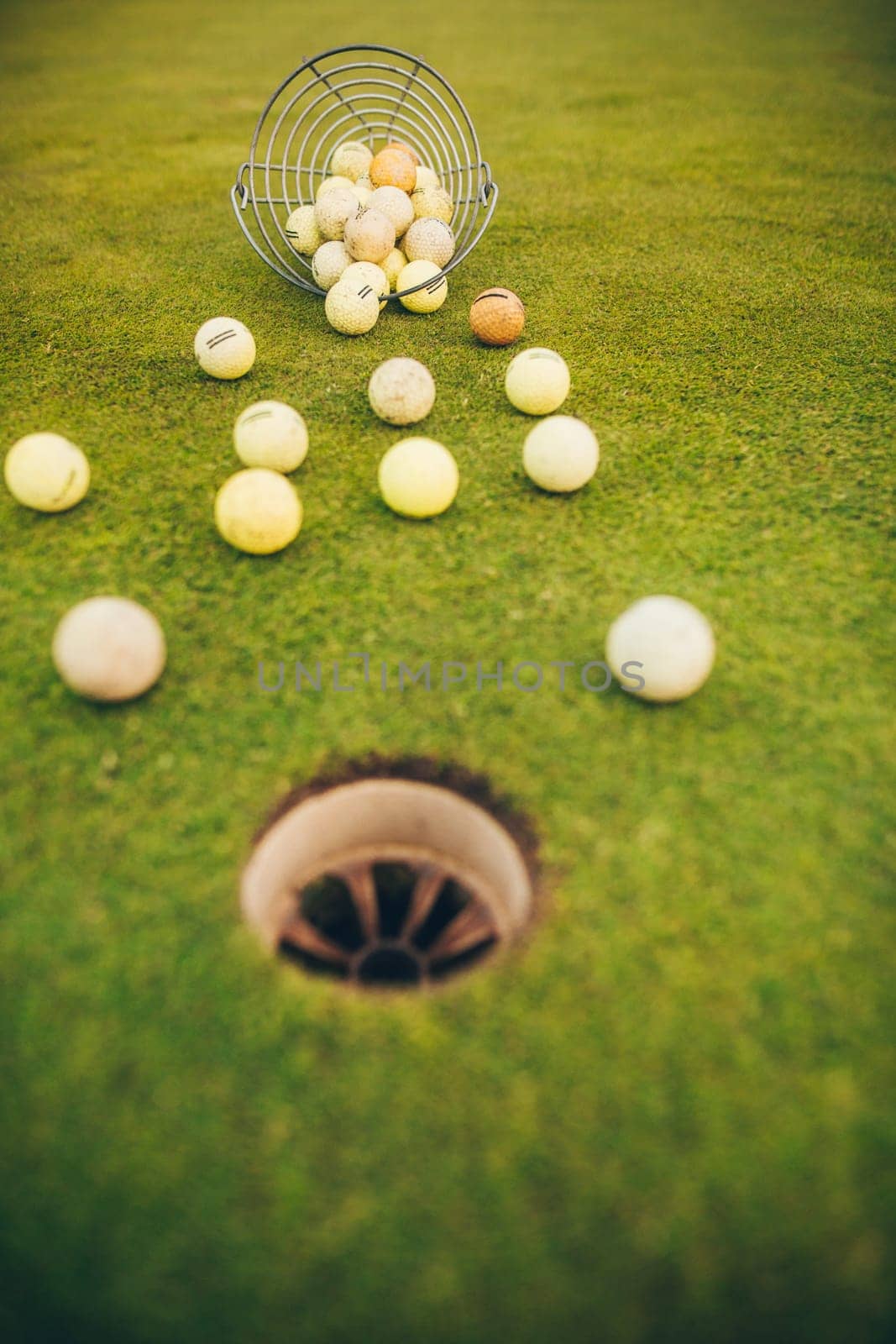 Close up of golf club and balls by the hole on a grass yard, sport concept