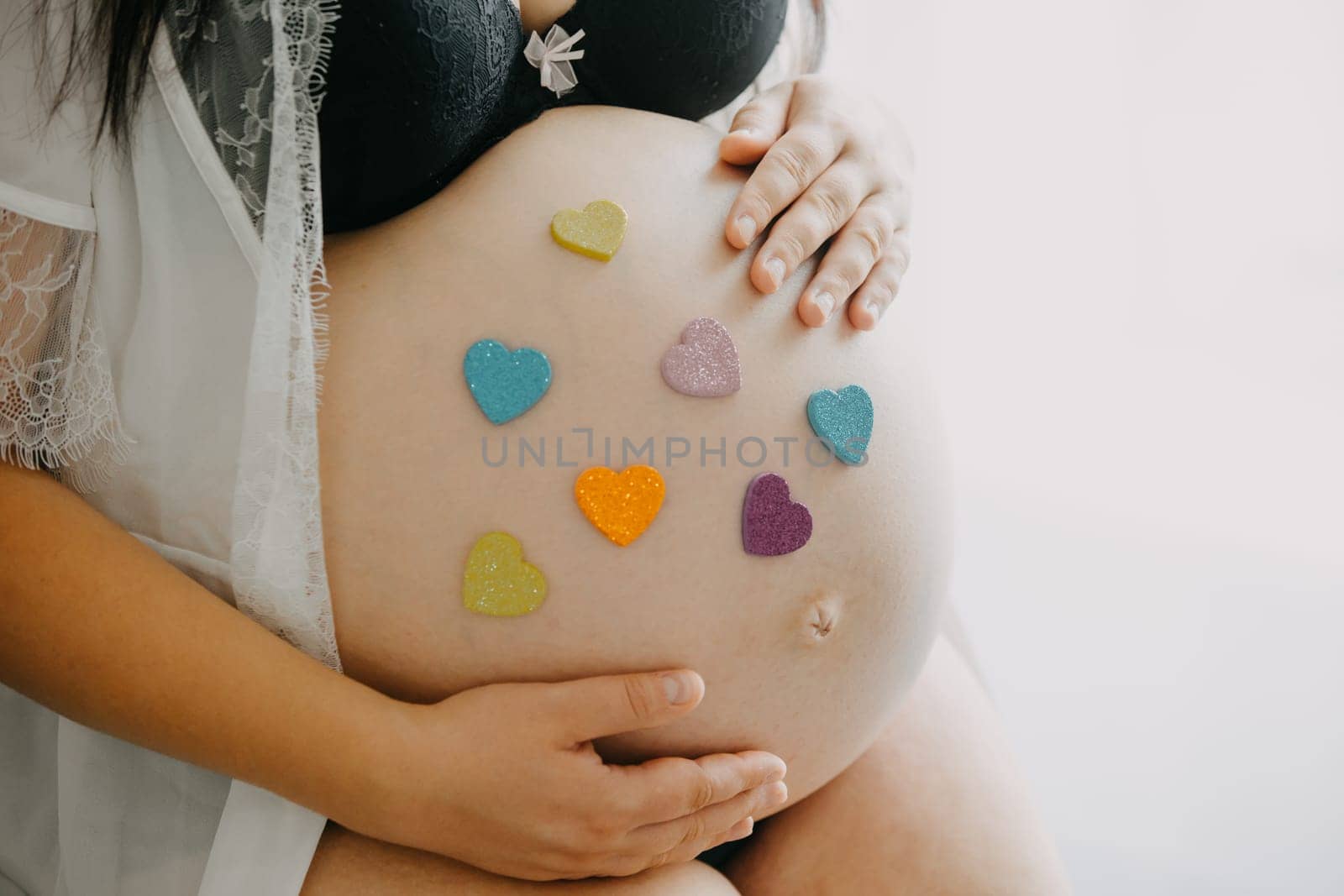 Young pregnant woman with belly and two heart stickers, pink and blue, a pregnancy concept