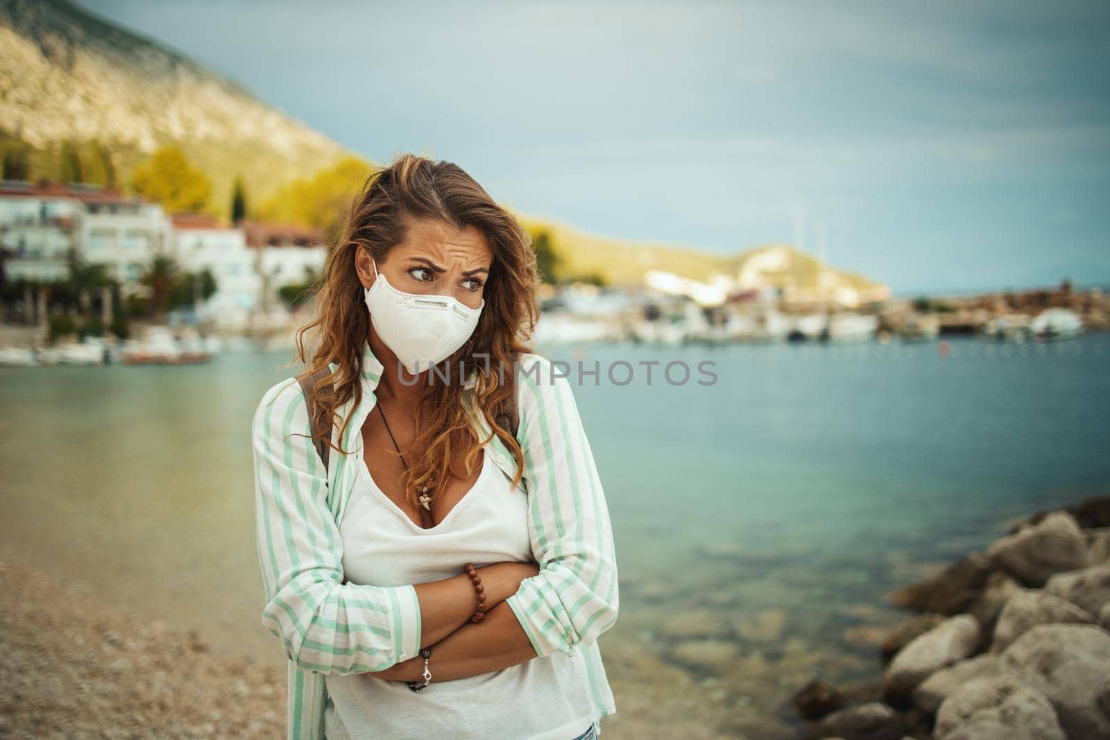 Shot of a concerned young woman with protective N95 mask at vacation on the seaside during the COVID-19.