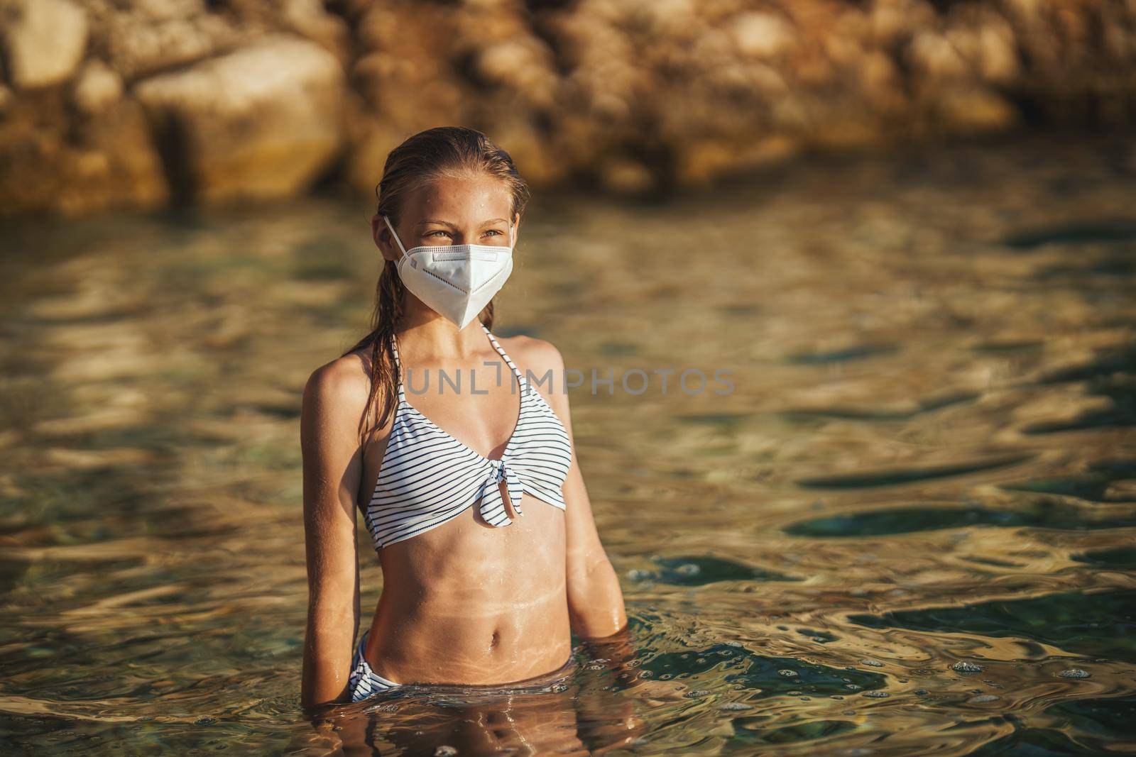 Shot of an happy teenager wearing surgical mask enjoying a vacation on the beach during the COVID-19.