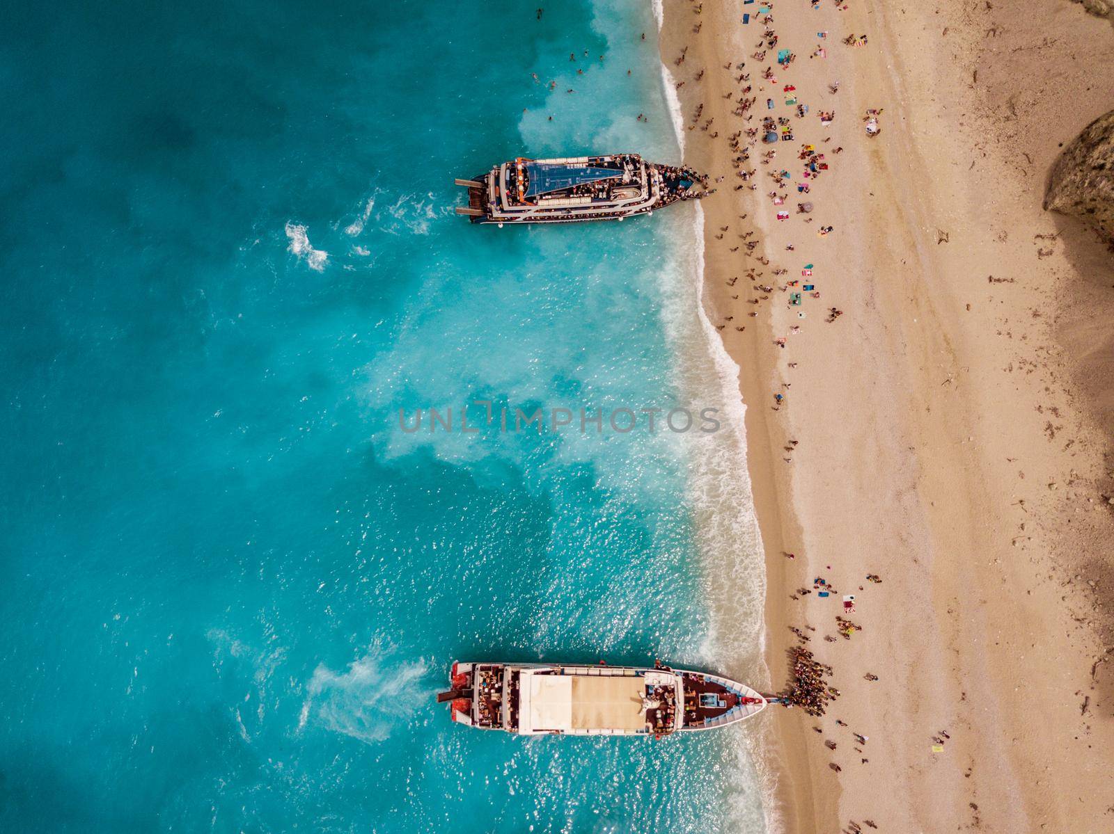 Aerial view from drone of amazing azure beach with rocky mountains and clear turquoise water of Mediterranean sea at sunny day. Tourist boats anchoring on the Egremni beach on Greek island Lefkada.