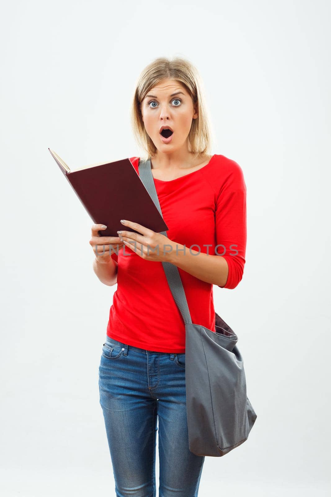 Portrait of surprised female student holding book.
