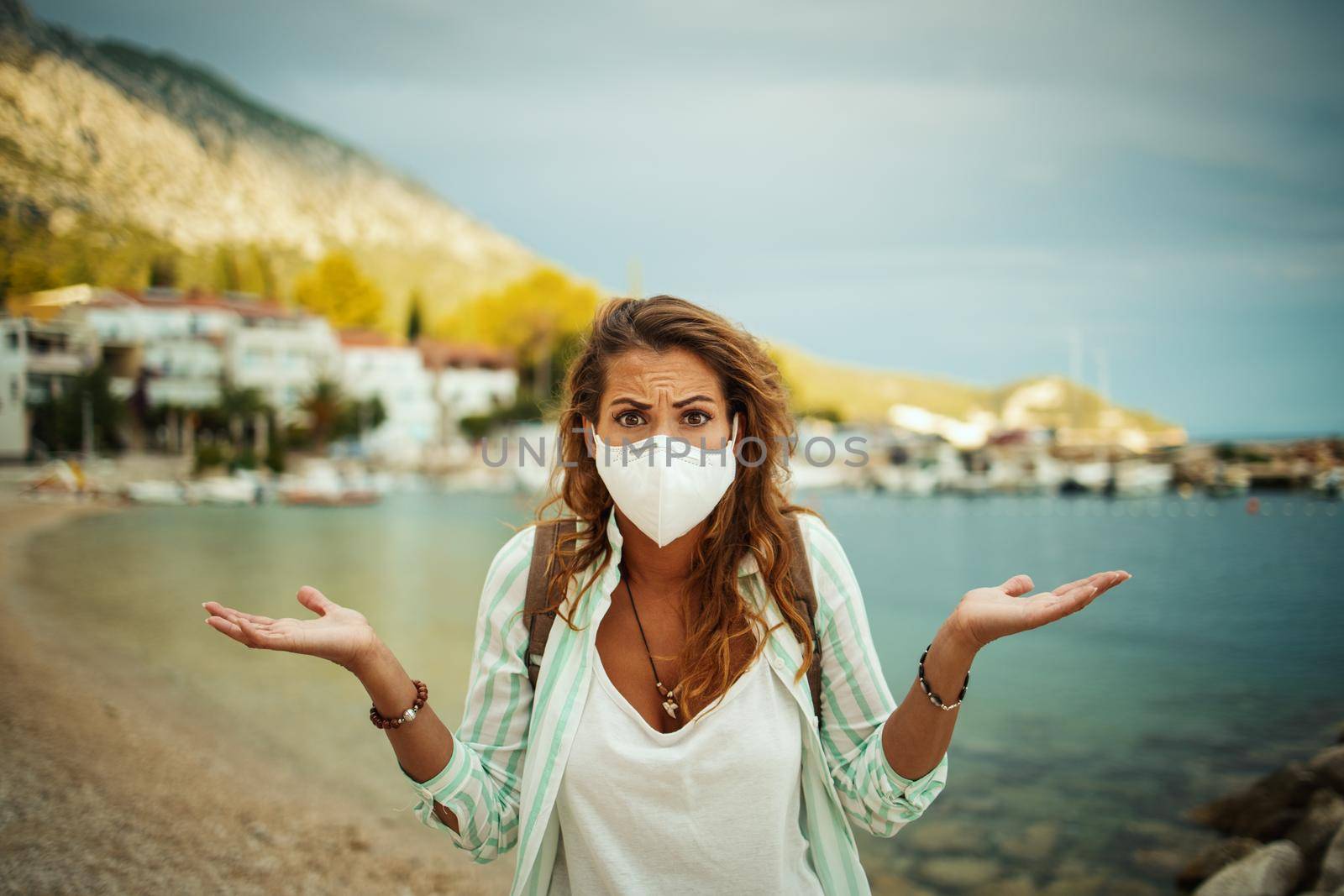 Shot of a concerned young woman with protective N95 mask at vacation on the seaside during the COVID-19.