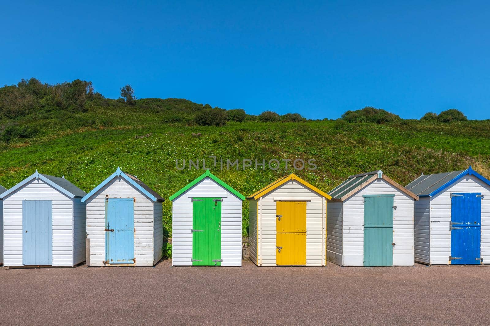 Colourful beach houses. Row of multicolored beach huts against blue sky.