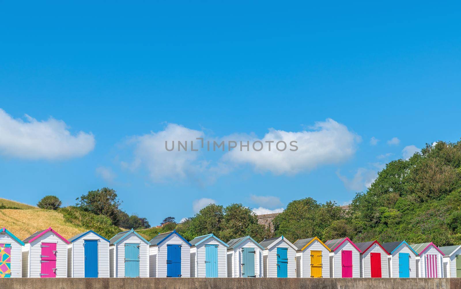 Colourful beach houses. Row of multicolored beach huts against blue sky.