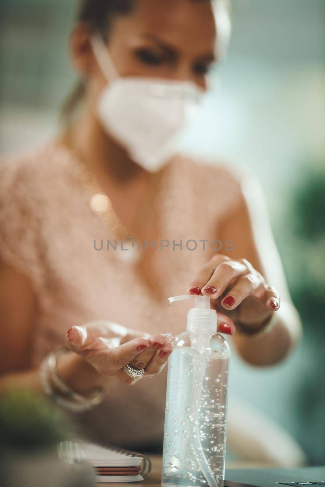 Shot of a attractive young businesswoman sitting alone in her home office and using antiseptic gel to disinfect his hands during COVID-19 pandemic.