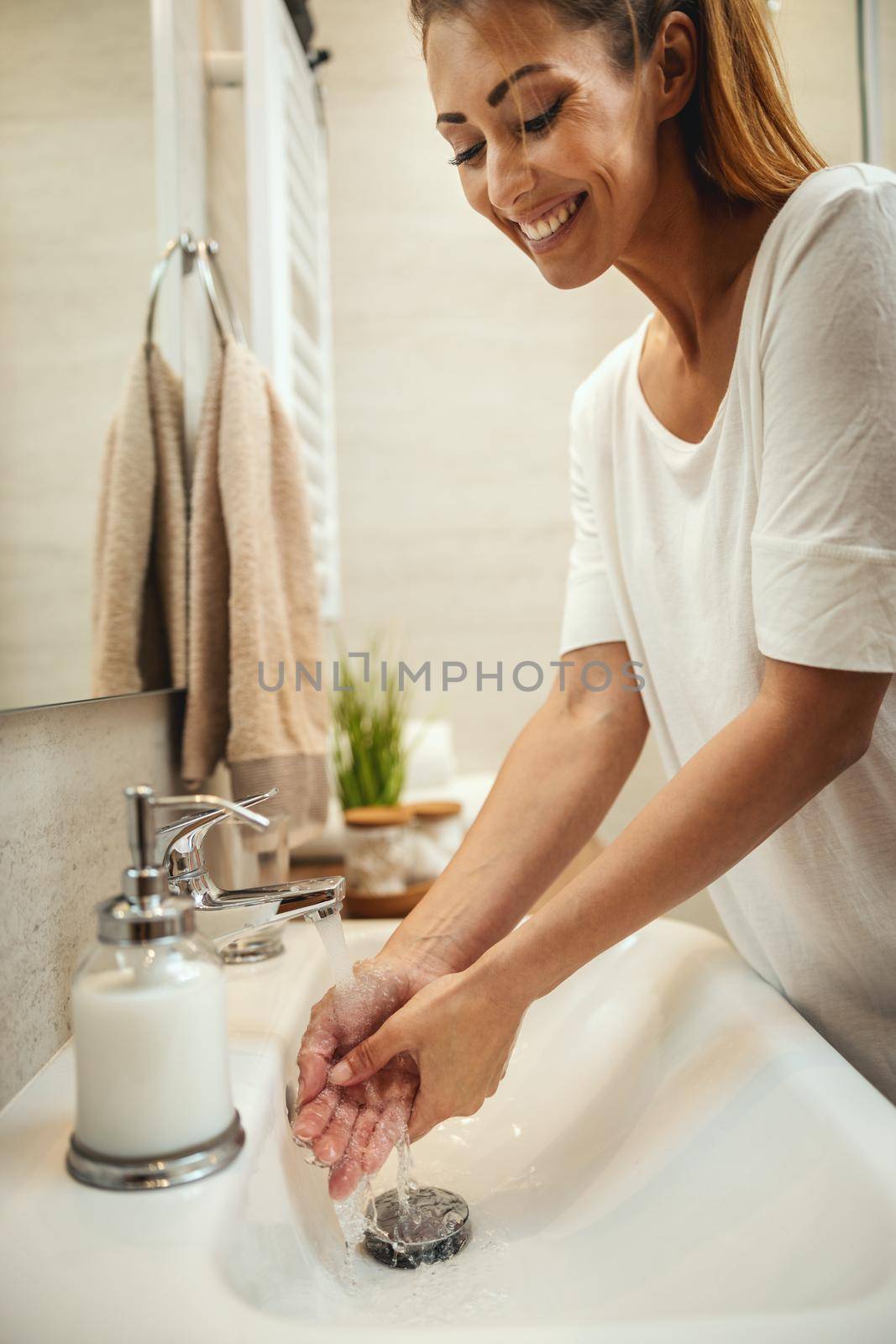 Smiling woman washing her hands with soap to prevent Coronavirus.