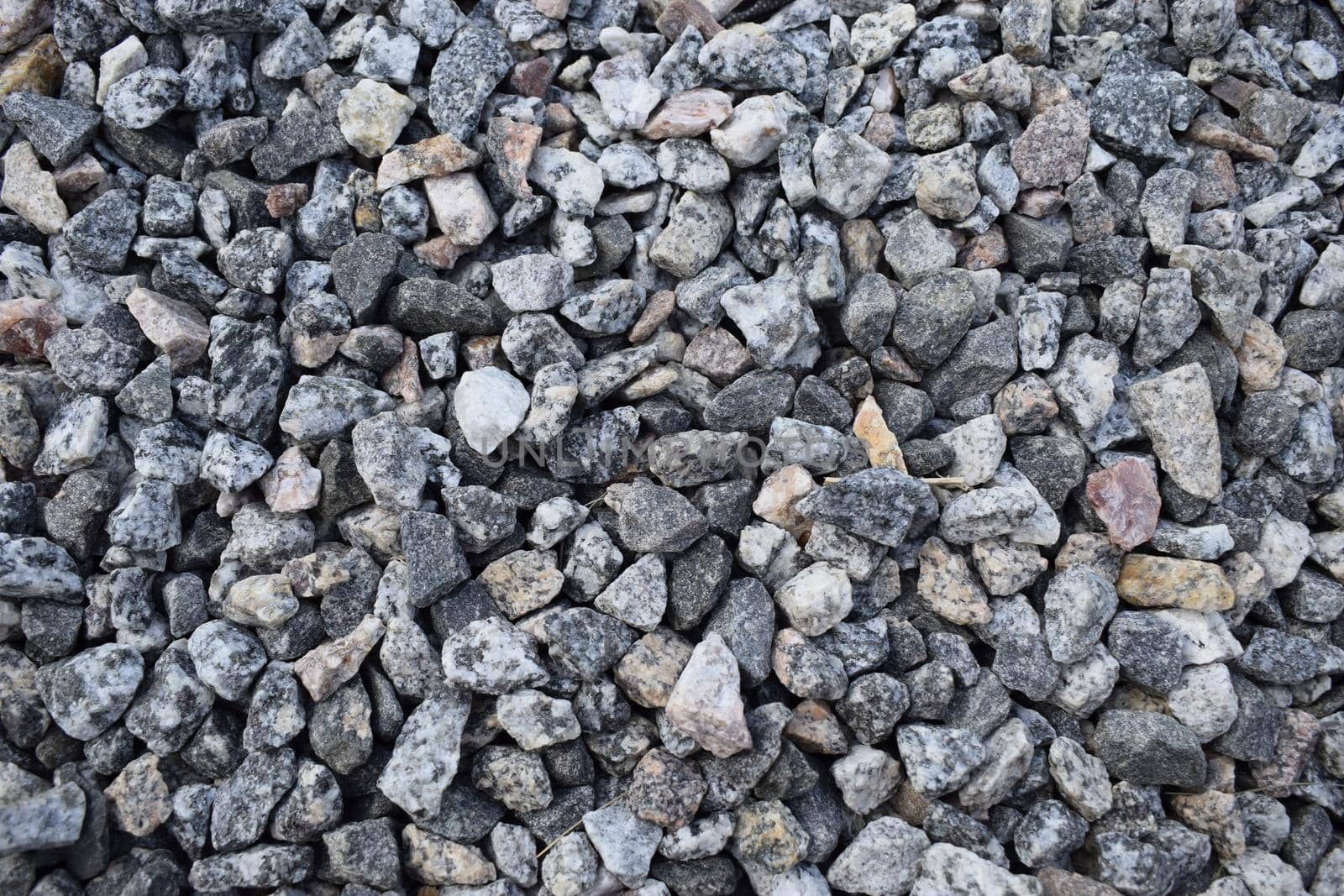Gravel Rock Texture. Crushed stone and gravel on the ground. Texture background brown stones on a black earth background. Image of broken stones and gravel