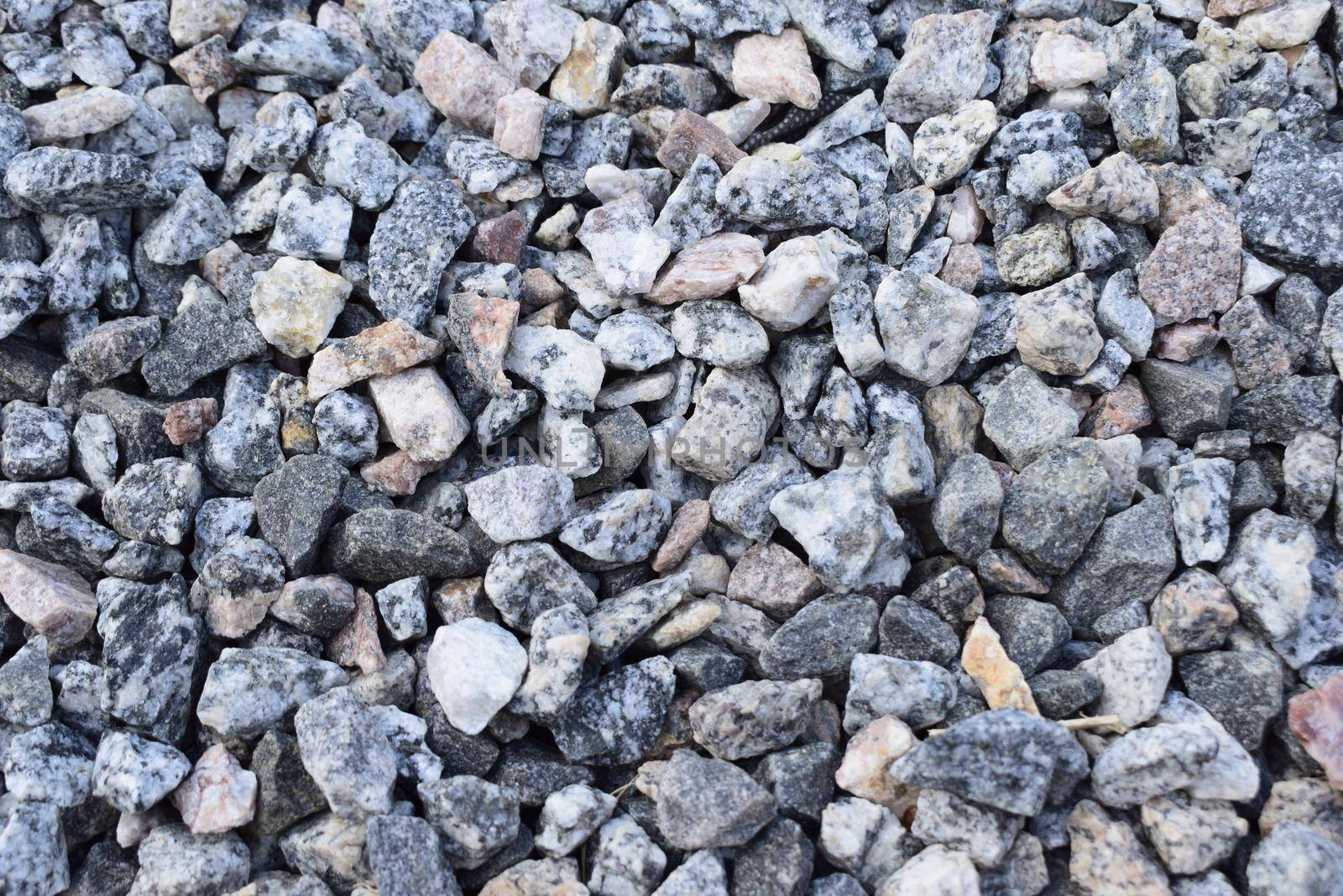 Gravel Rock Texture. Crushed stone and gravel on the ground. Texture background brown stones on a black earth background. Image of broken stones and gravel