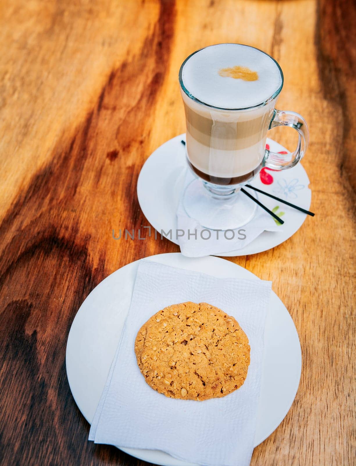 Close up of cookie and cappuccino on wooden table. Top view glass of hot cappuccino with cookie on wooden background by isaiphoto