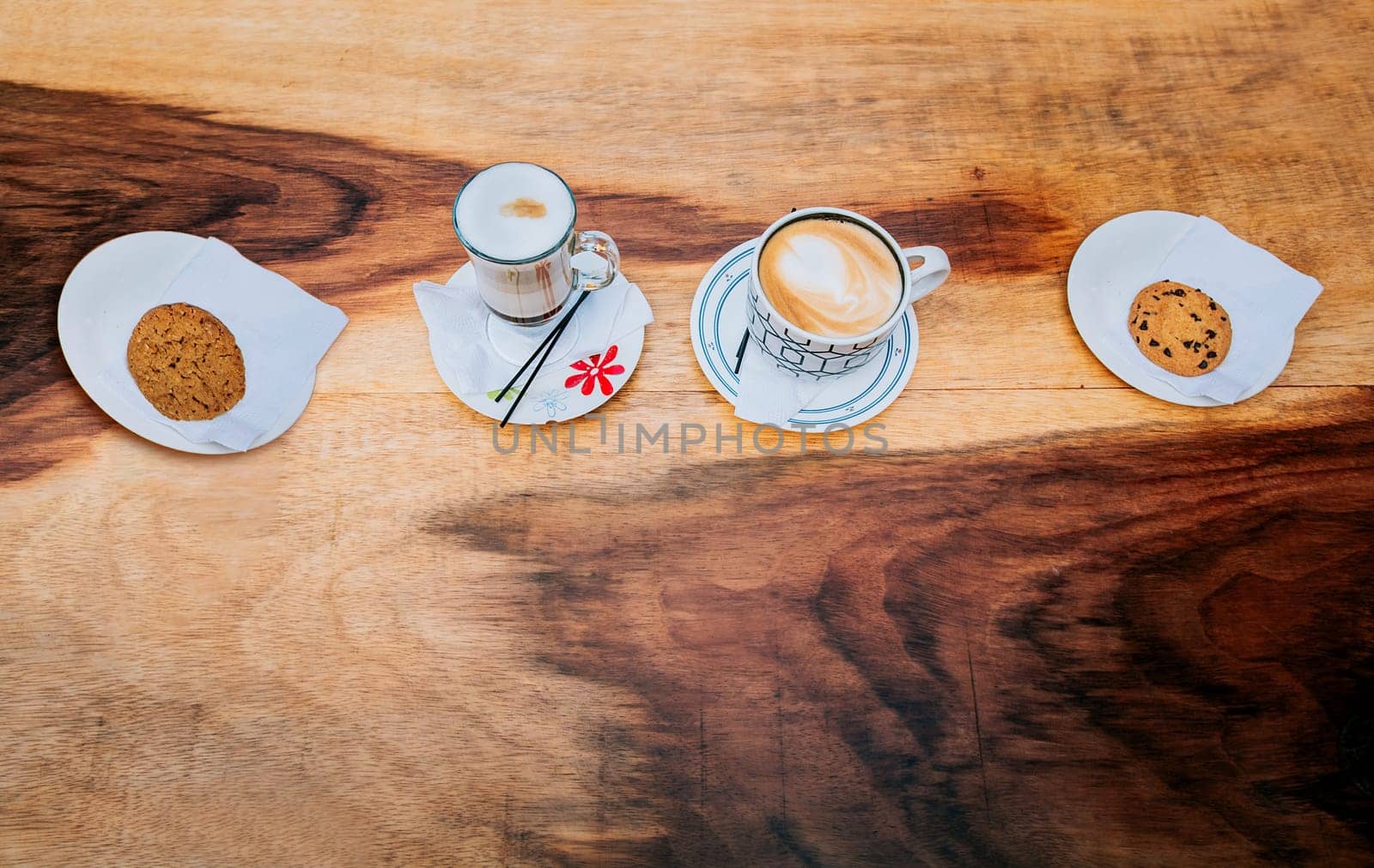 Top view of hot cappuccinos with cookie on wooden background. High angle view of cappuccinos with cookies on wooden table by isaiphoto