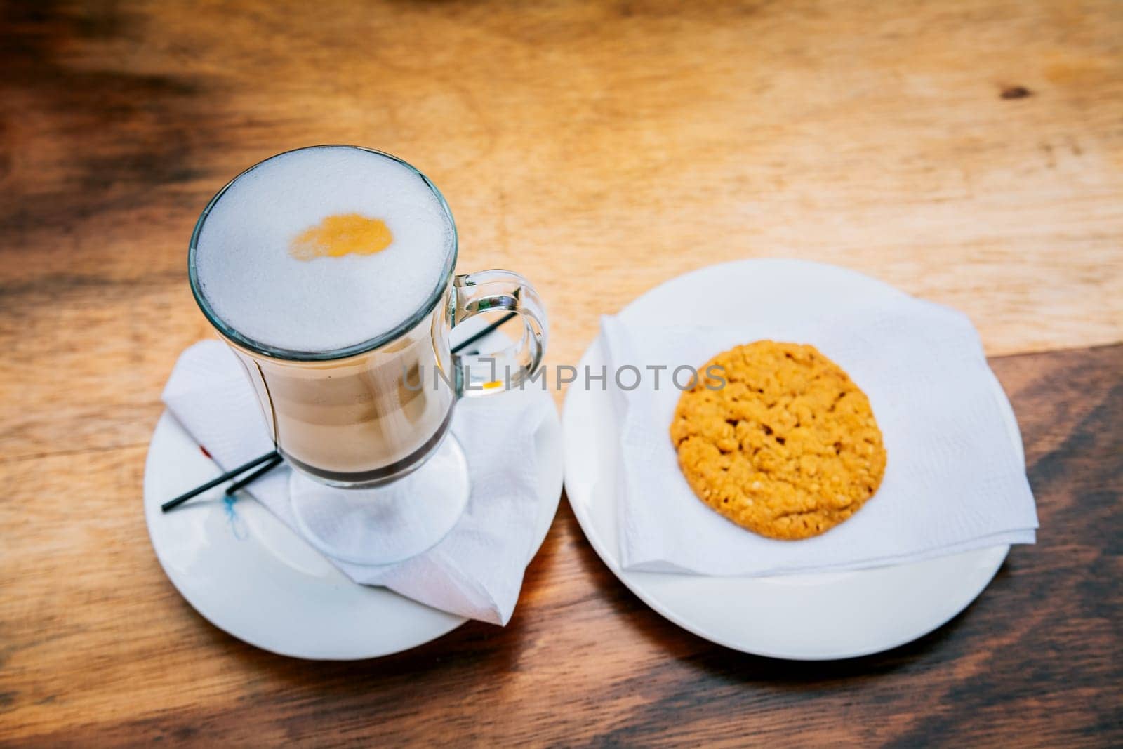 Delicious hot cappuccino coffee with cookie on wooden background. Cup of cappuccino with cookie on wooden table by isaiphoto