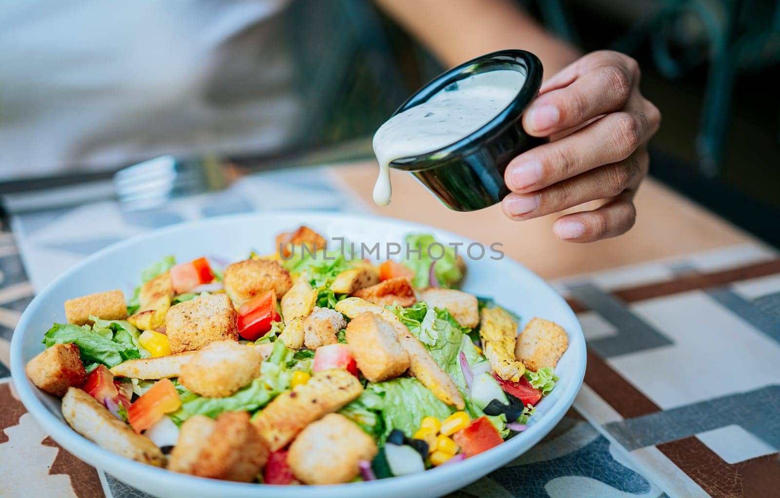 Close up of hand preparing a vegetable salad. Concept of healthy food and lifestyle, Hand putting dressing on a caesar salad