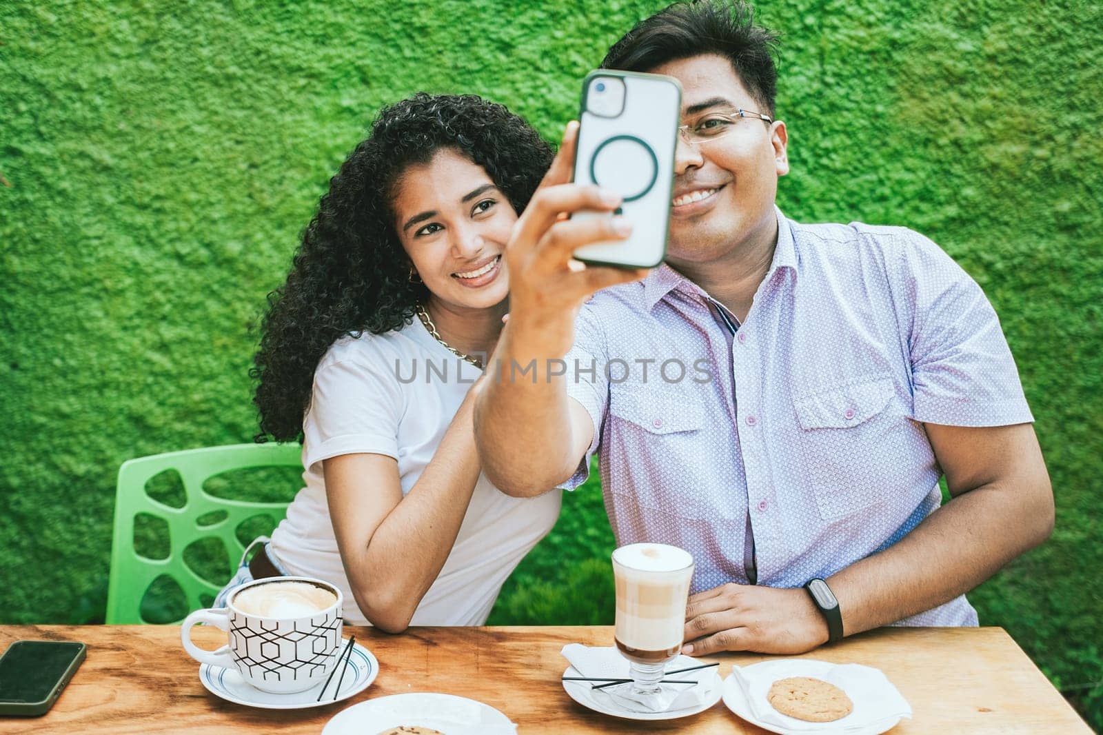 Two latin friends enjoying a coffee and taking a selfie. Happy latin friends having a coffee and taking a selfie by isaiphoto