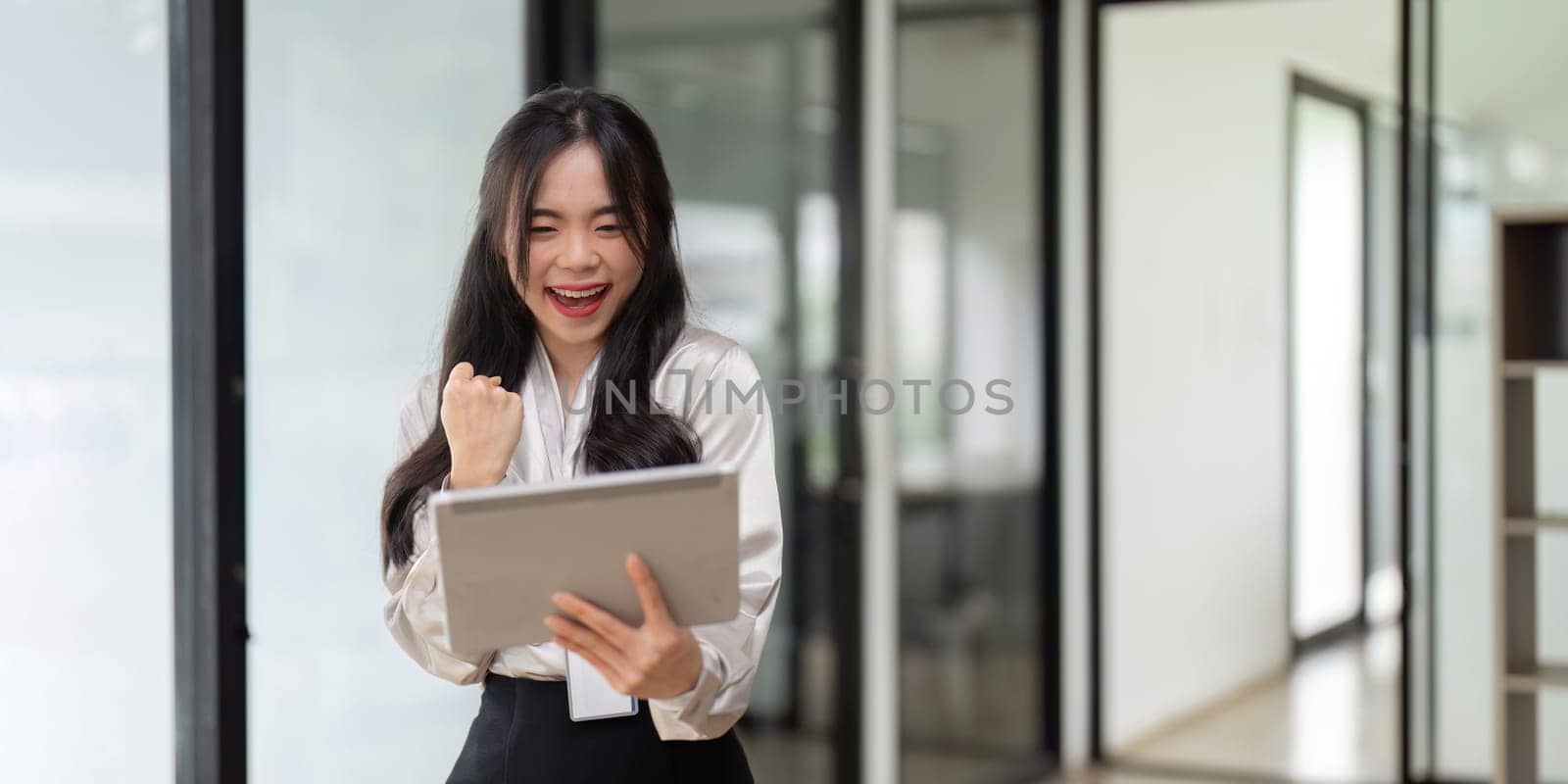 Young businesswoman working successfully in office while standing near window.