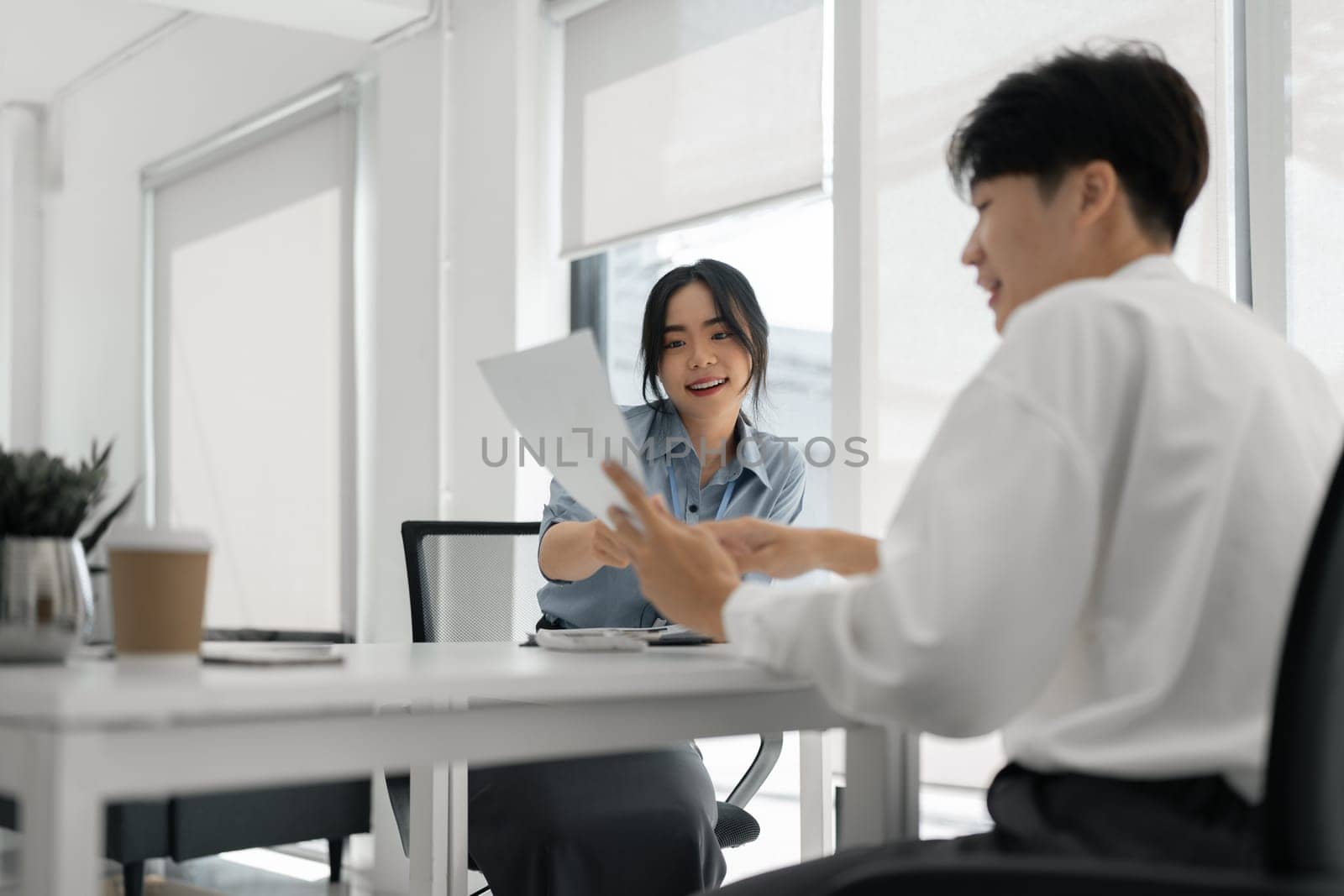 Two Asian colleagues discussing work Businessman holding a tablet in the office.