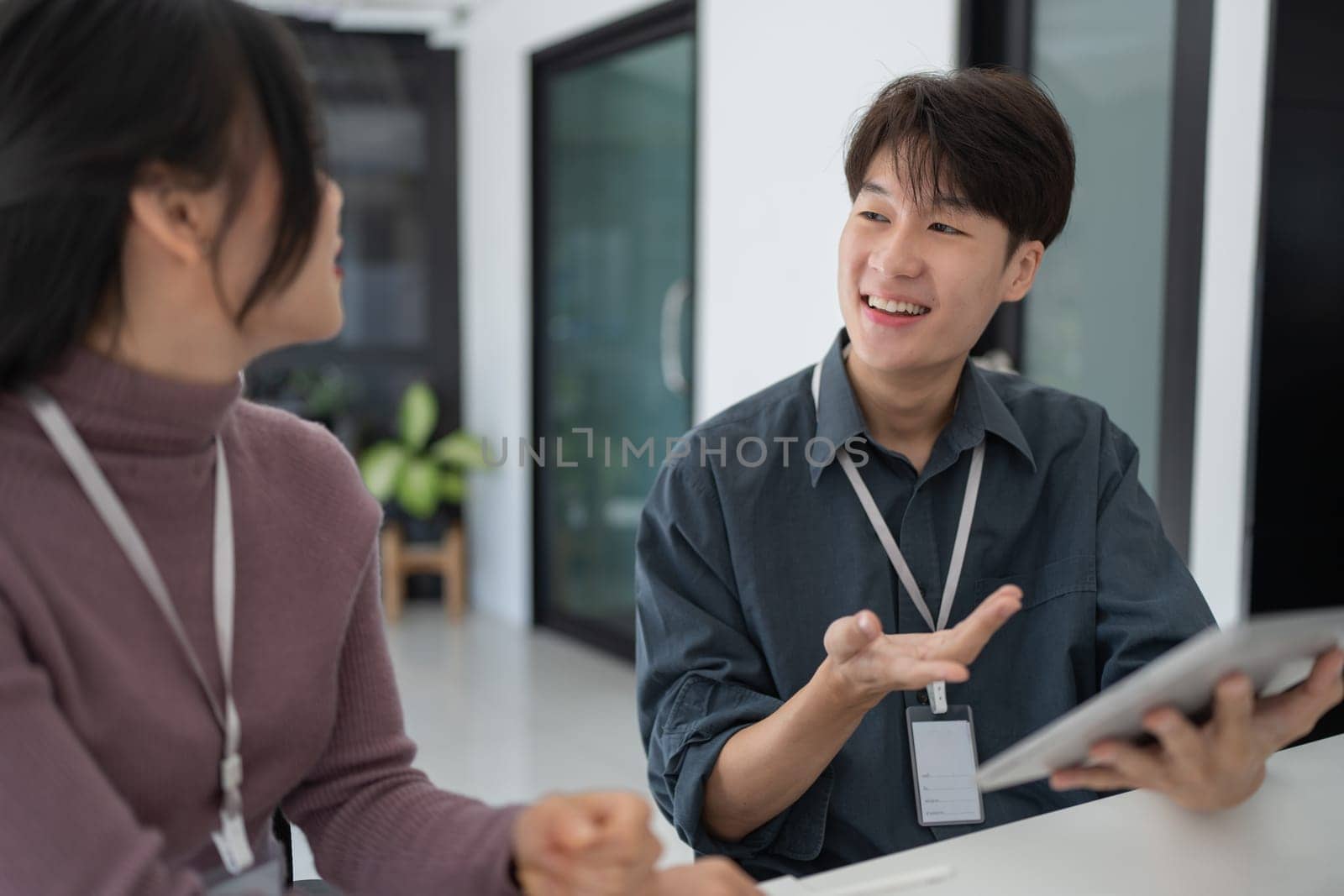 Two asian business worker looking at tablet discussing corporate strategy in teamwork, working on computer laptop in office at office.