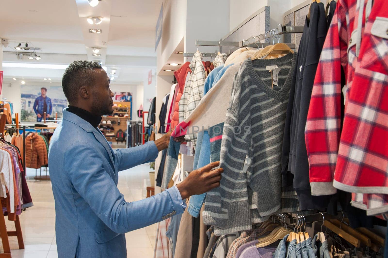 copyspace of a black man shopaholic choosing a sweater in a clothing store. High quality photo