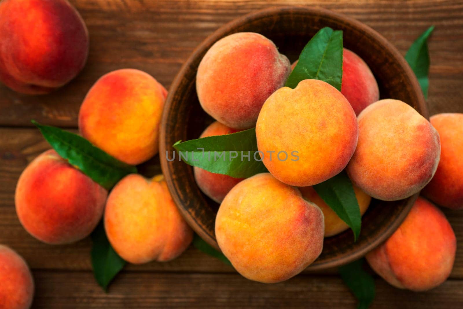 Ripe and tasty and juicy peaches lie on a plate on a wooden table. Large peaches on rustic wooden background, selective focus.