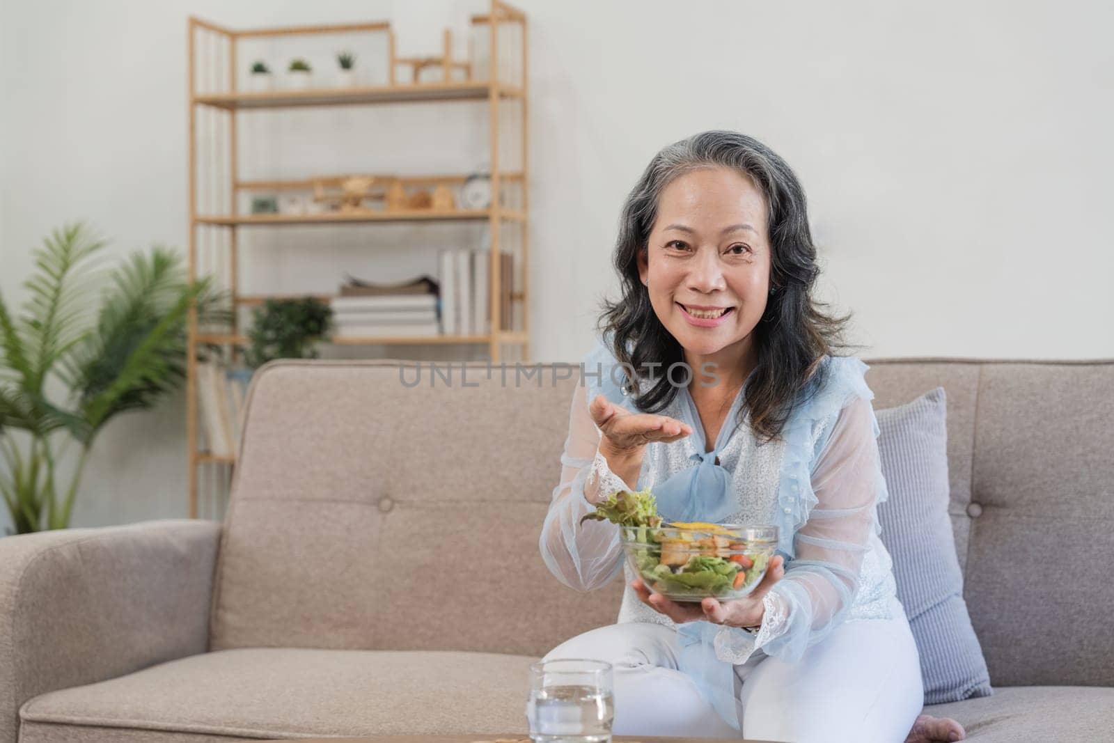 Senior Asian woman eating fresh and clean vegetarian salad at home. Health care concept by nateemee