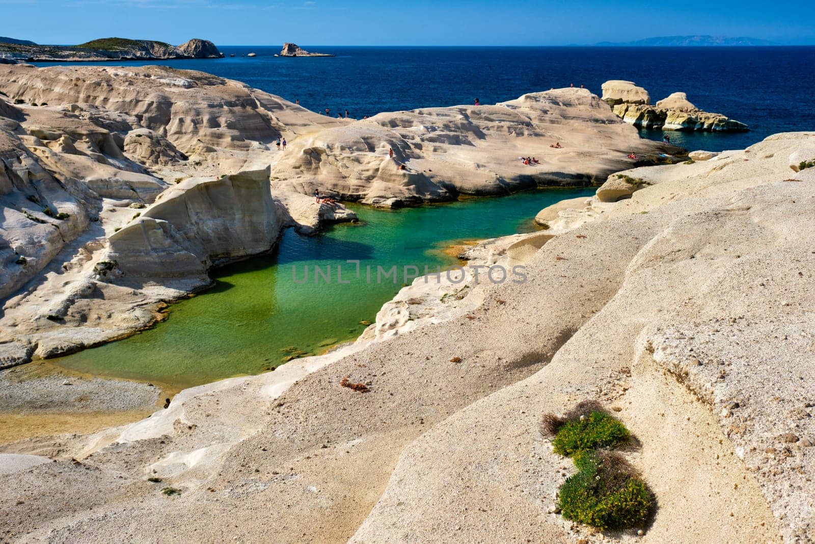 White rocks of famous tourist attraction of Milos island Sarakiniko beach with tourist relax and Aegean sea, Milos island , Greece