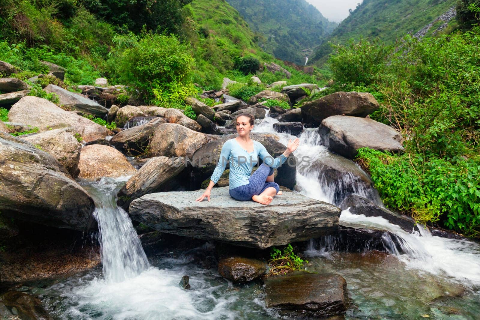 Woman doing Ardha matsyendrasana asana outdoors by dimol