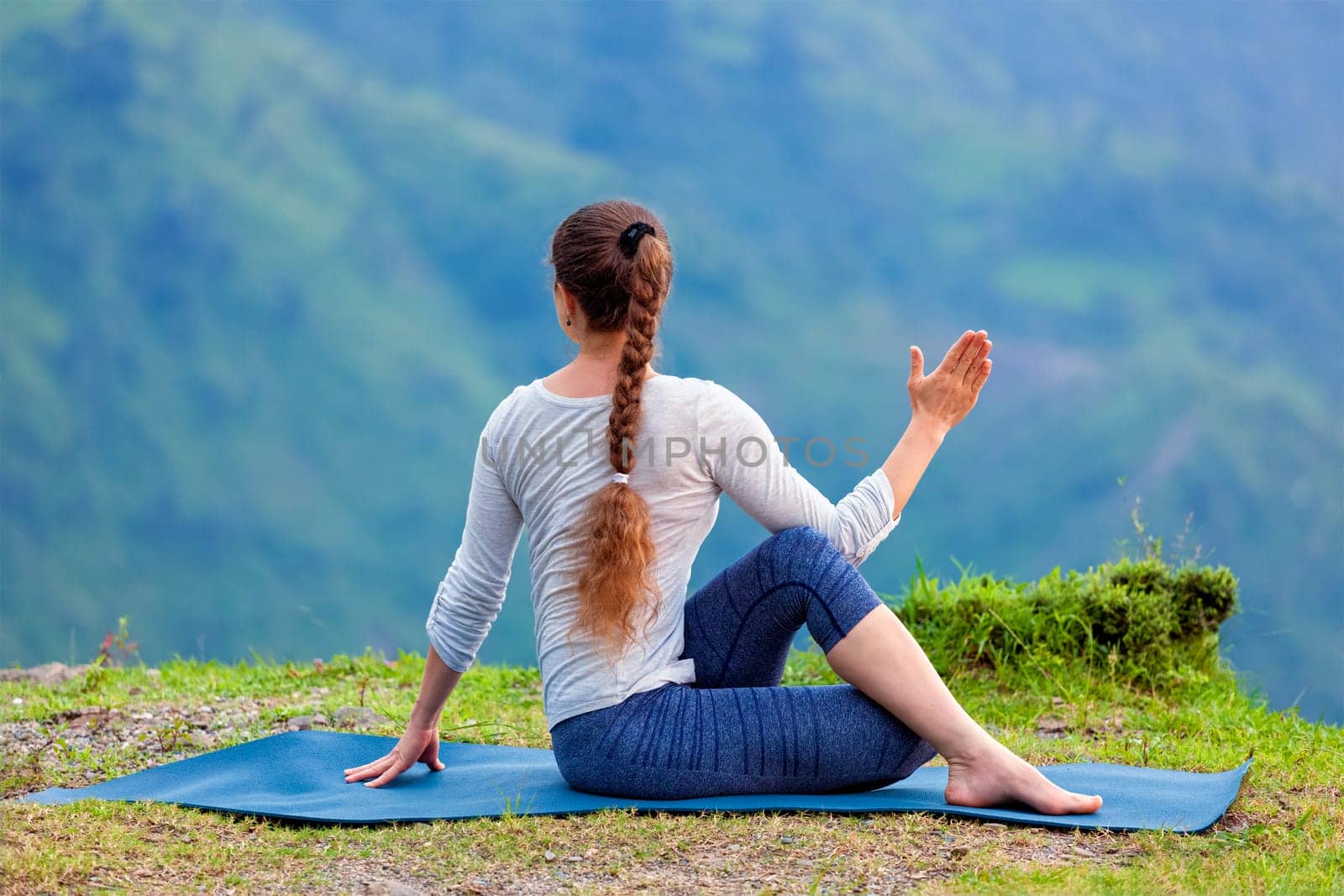 Woman practices yoga asana outdoors by dimol