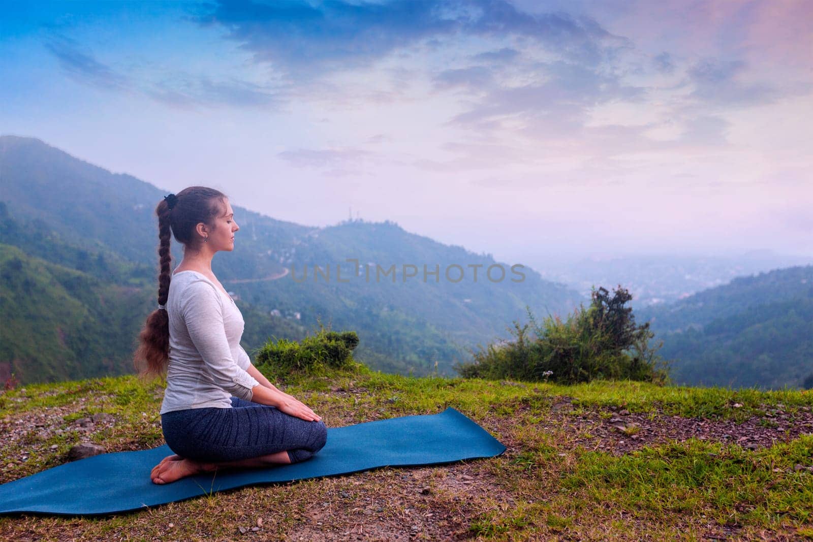 Yoga exercise outdoors - woman doing Yoga asana Virasana (Vajrasana) Hero pose in Himalayas in India on sunset