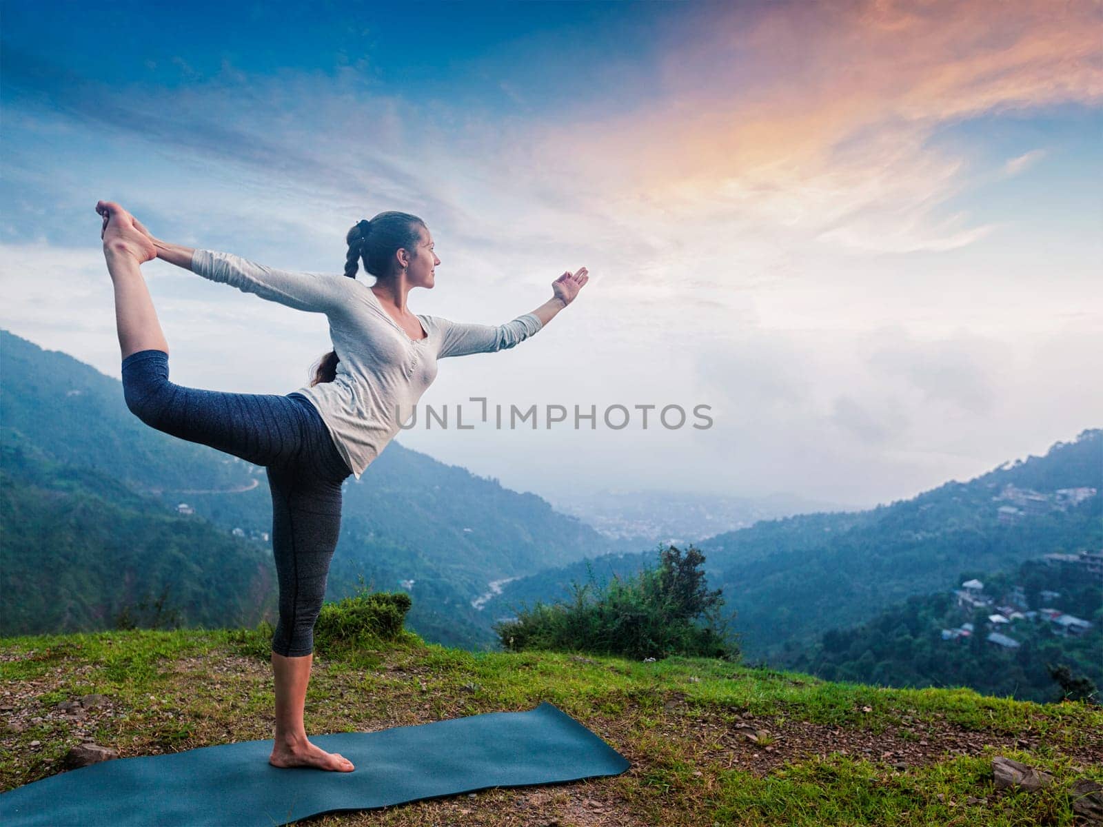 Woman doing yoga asana Natarajasana - Lord of the dance pose outdoors at waterfall in Himalayas