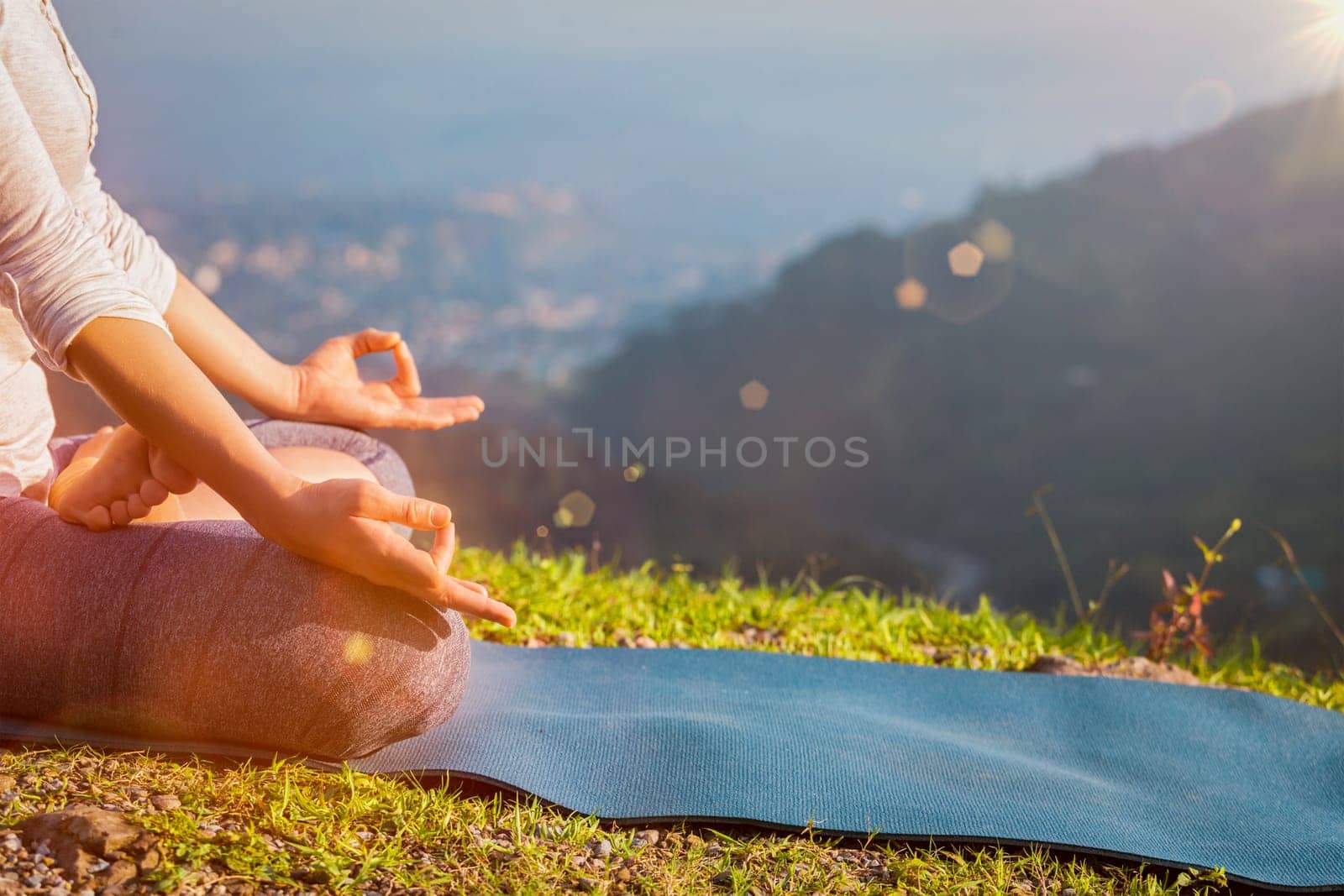Close up of woman in Padmasana yoga lotus pose with chin mudra outdoors with copyspace. With light leak and lens flare