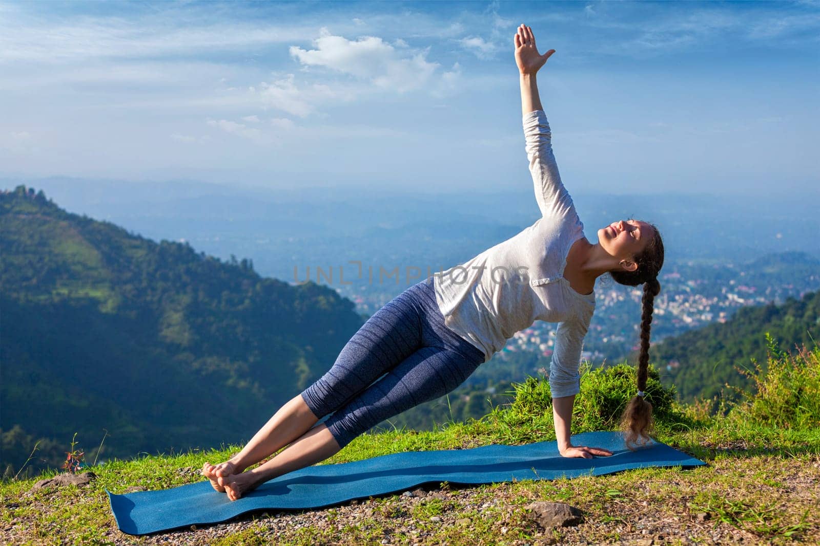 Woman doing yoga asana Vasisthasana - side plank pose outdoors by dimol