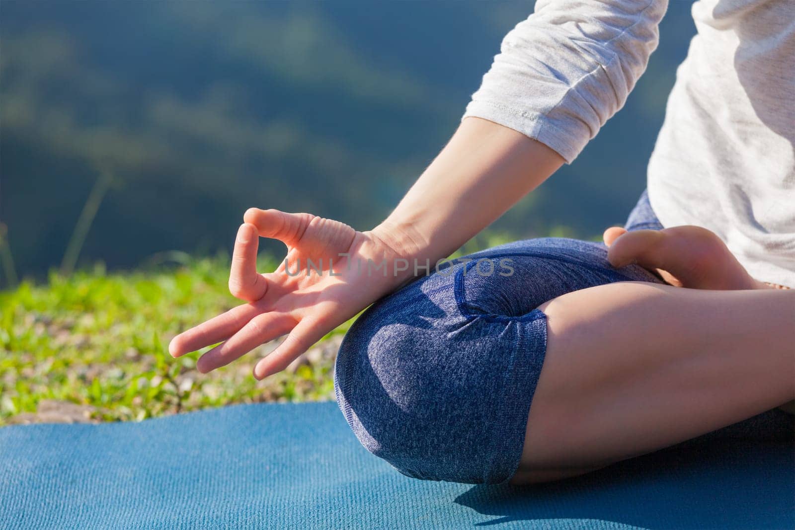 Meditation relaxation concept background - close up of woman in Padmasana yoga lotus pose with chin mudra outdoors with copyspace