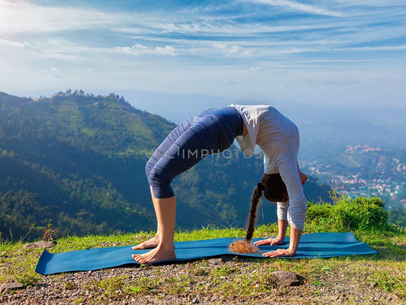 Yoga outdoors - young sporty fit woman doing Ashtanga Vinyasa Yoga asana Urdhva Dhanurasana - upward bow pose - in Himalayas mountains in the morning Himachal Pradesh, India