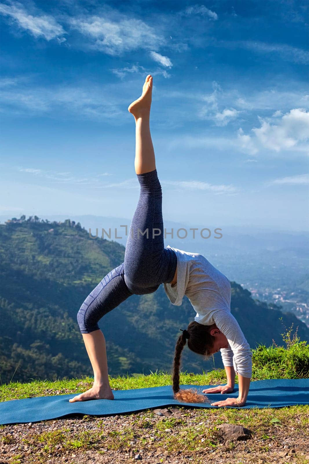 Woman doing yoga asana outdoors by dimol