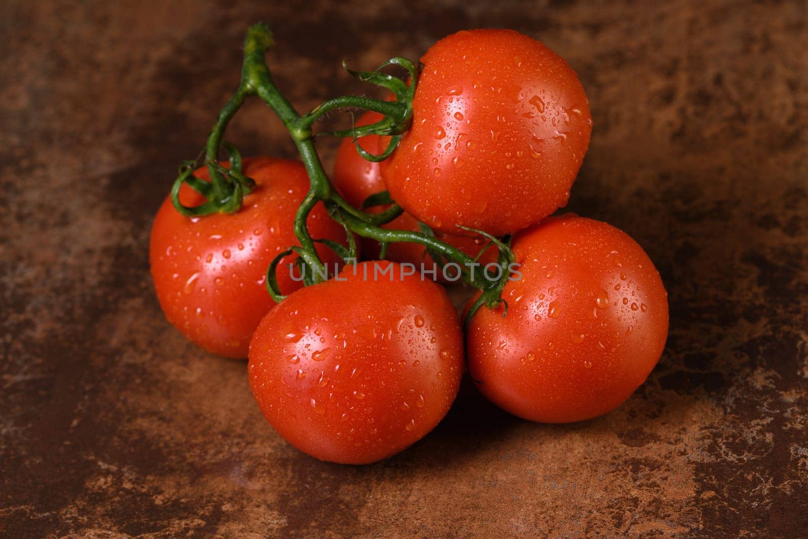 Fresh ripe red tomato branch on a rusty, redhead table with water drops. Close-up. Horizontal  photo. Poster for vegetable market or shop.