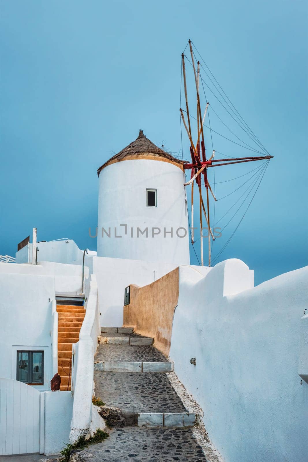 Old traditional whitewashed greek windmill on Santorini island in Oia town with stairs in street. Oia village, Santorini, Greece